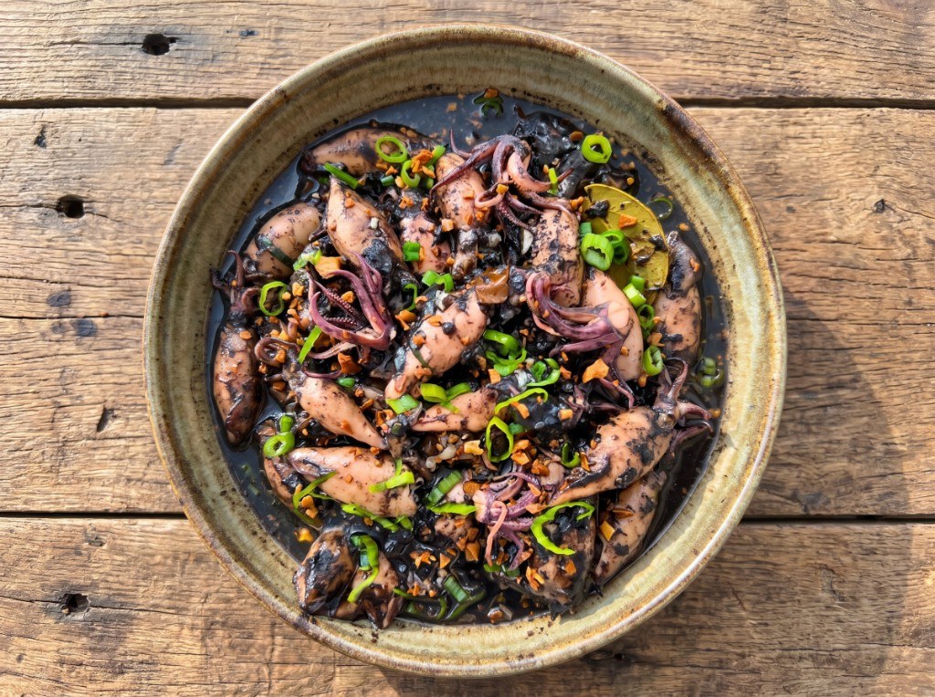 Bowl of adobong pusit: squid rings and tentacles in dark glossy soy-vinegar sauce with garlic