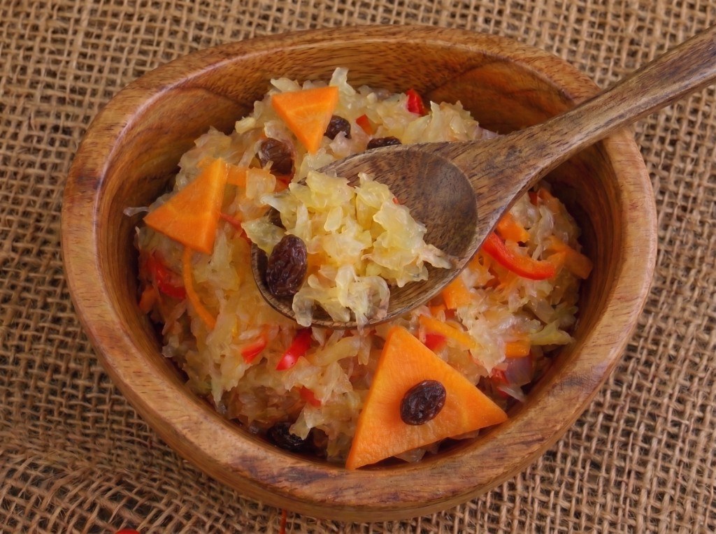 Wooden bowl of Filipino atchara: shredded pickled green papaya with carrot, raisins, and red pepper