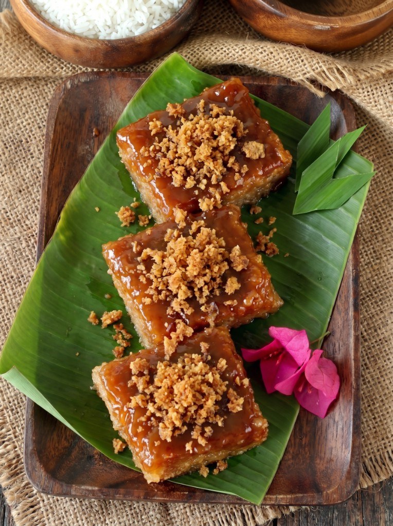 Three slices of biko on banana leaf, glossy coconut caramel topping with latik in the center