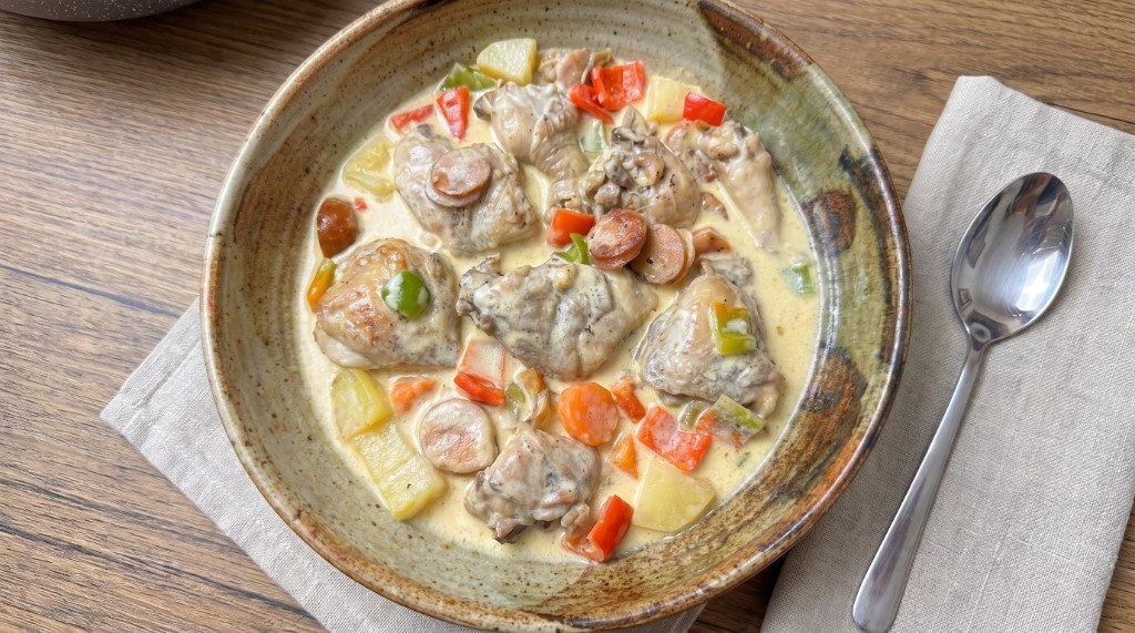 Bowl of Filipino chicken pastel with bone-in chicken, potato, carrot, sausage, and bell pepper in creamy sauce