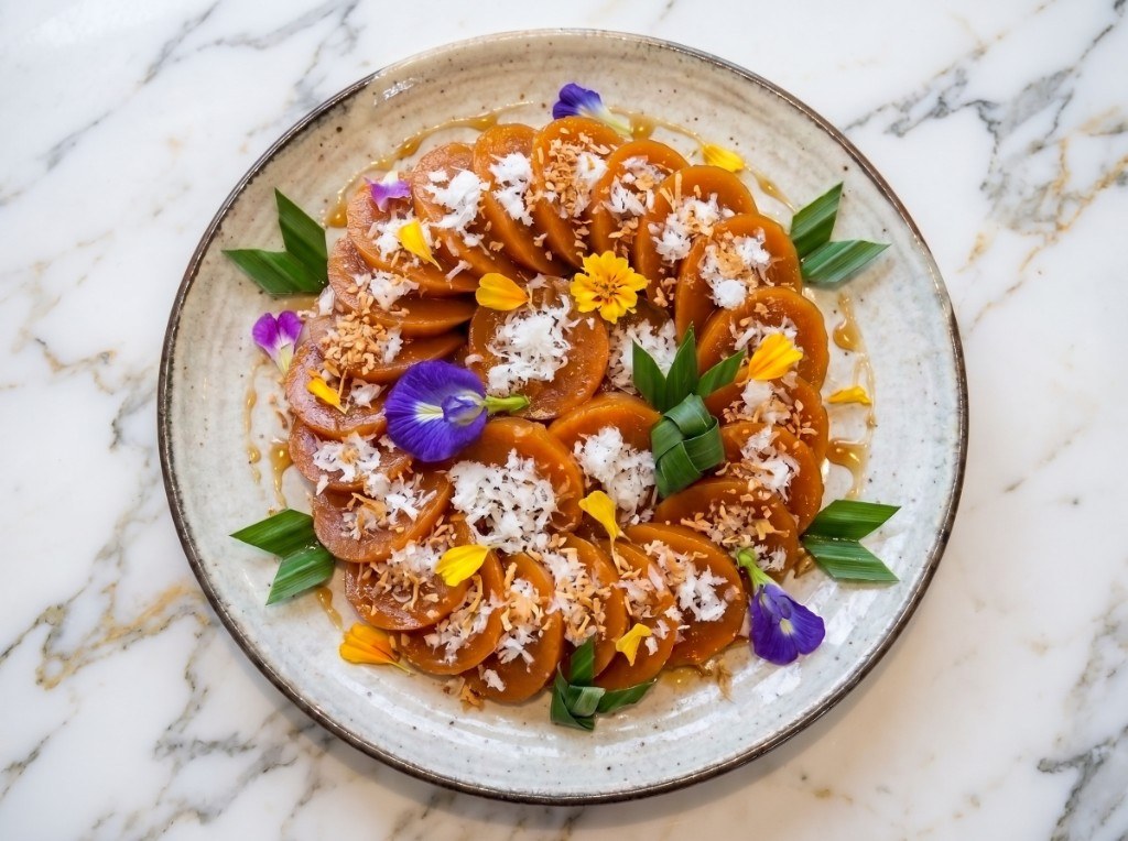 Plate of brown kutsinta rice cakes topped with grated coconut, toasted coconut, and edible flowers