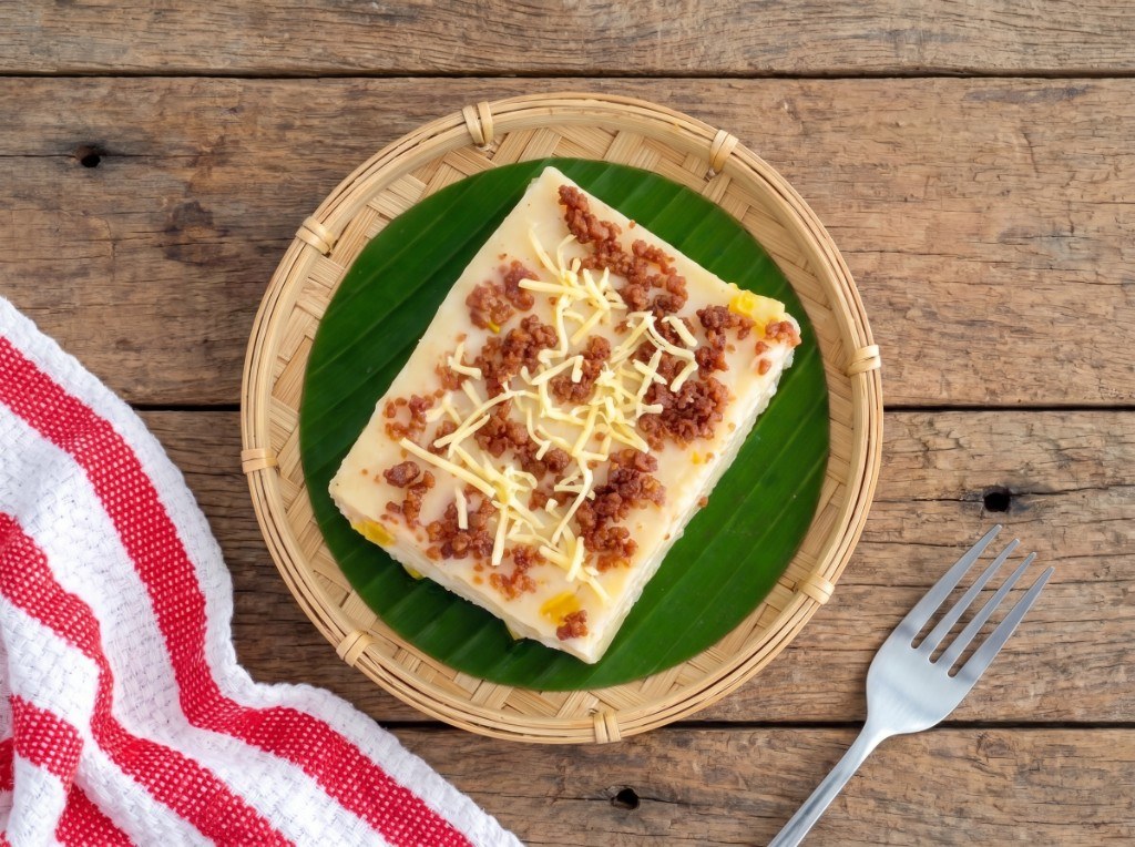 Squares of white maja blanca coconut pudding with corn kernels and brown latik on top
